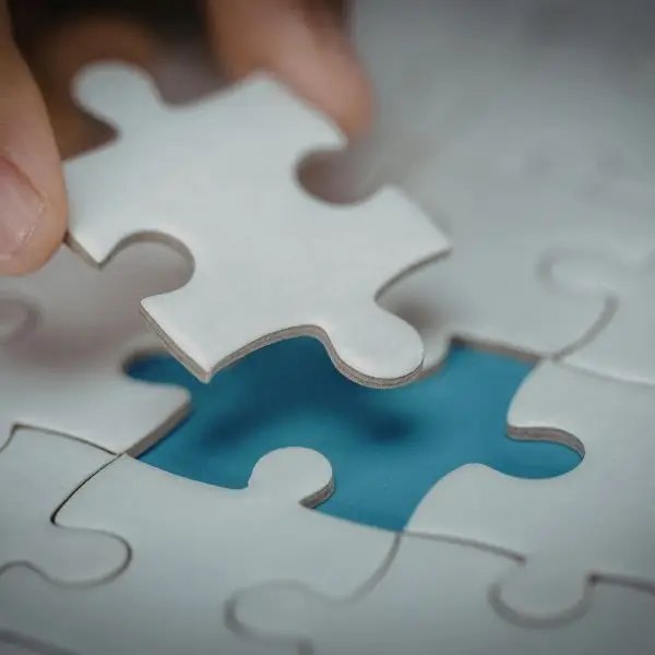 a hand putting the final piece into a jigsaw puzzle